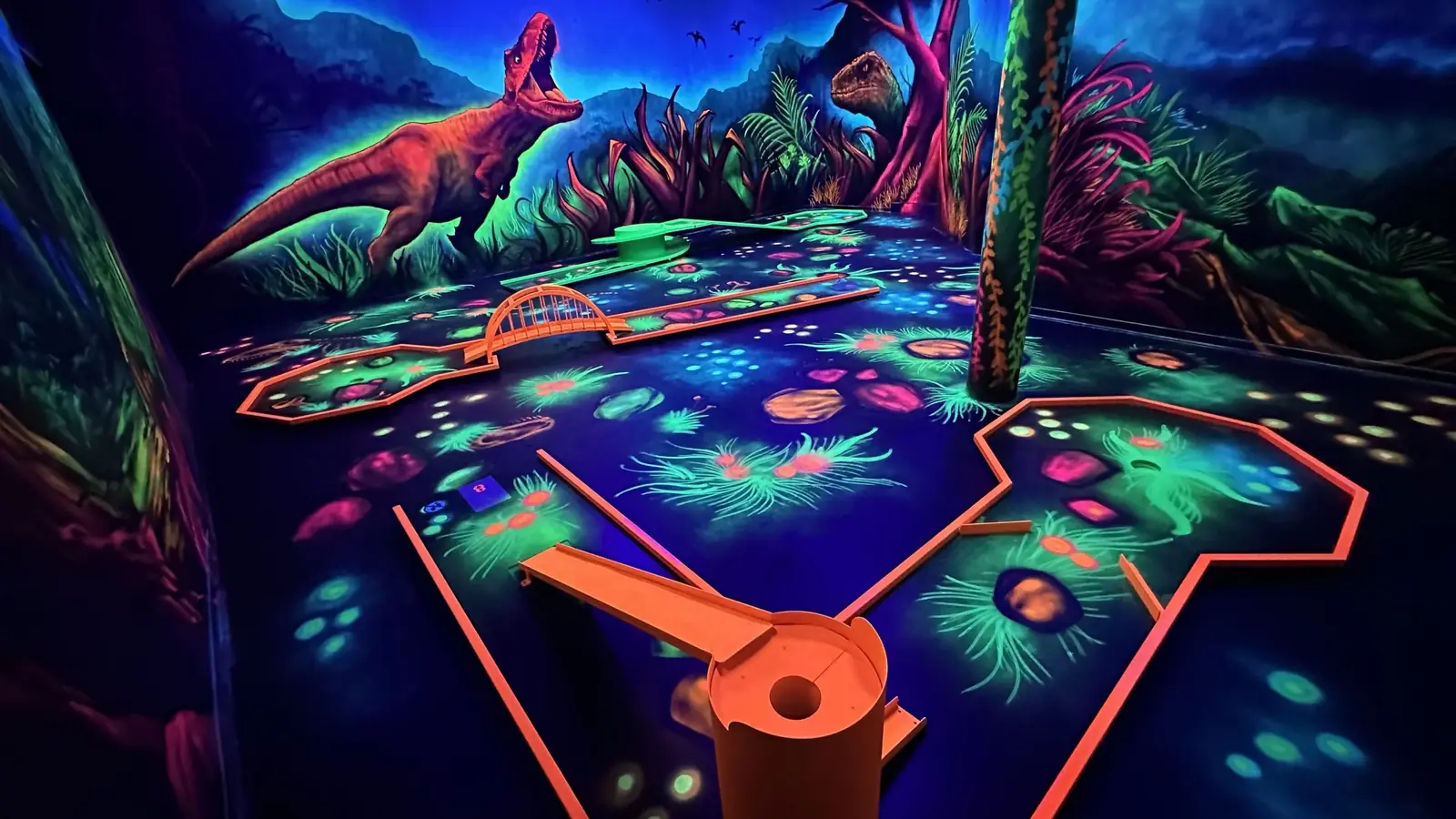 Moonlight-Minigolfbahn mit Dinosaurier-Kulisse im Schwarzlicht